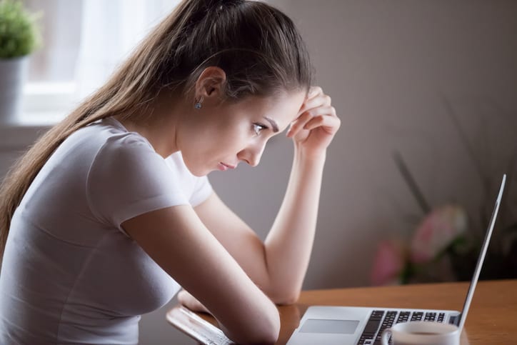 Young woman thinking looking on computer screen